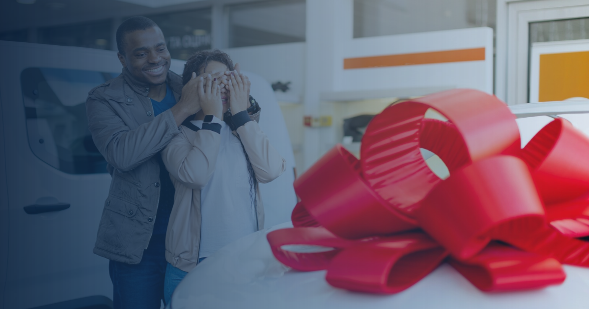 Couple purchasing new car at dealership with red bow on car.